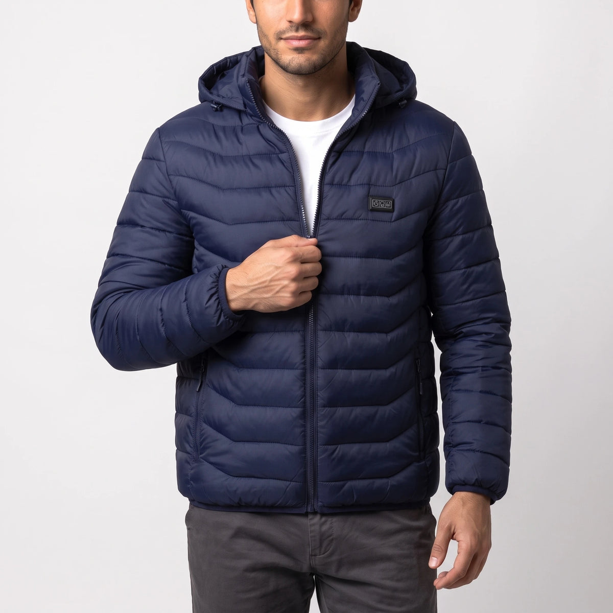Veste chauffante bleu marine à capuche portée par un homme, une main sur la fermeture