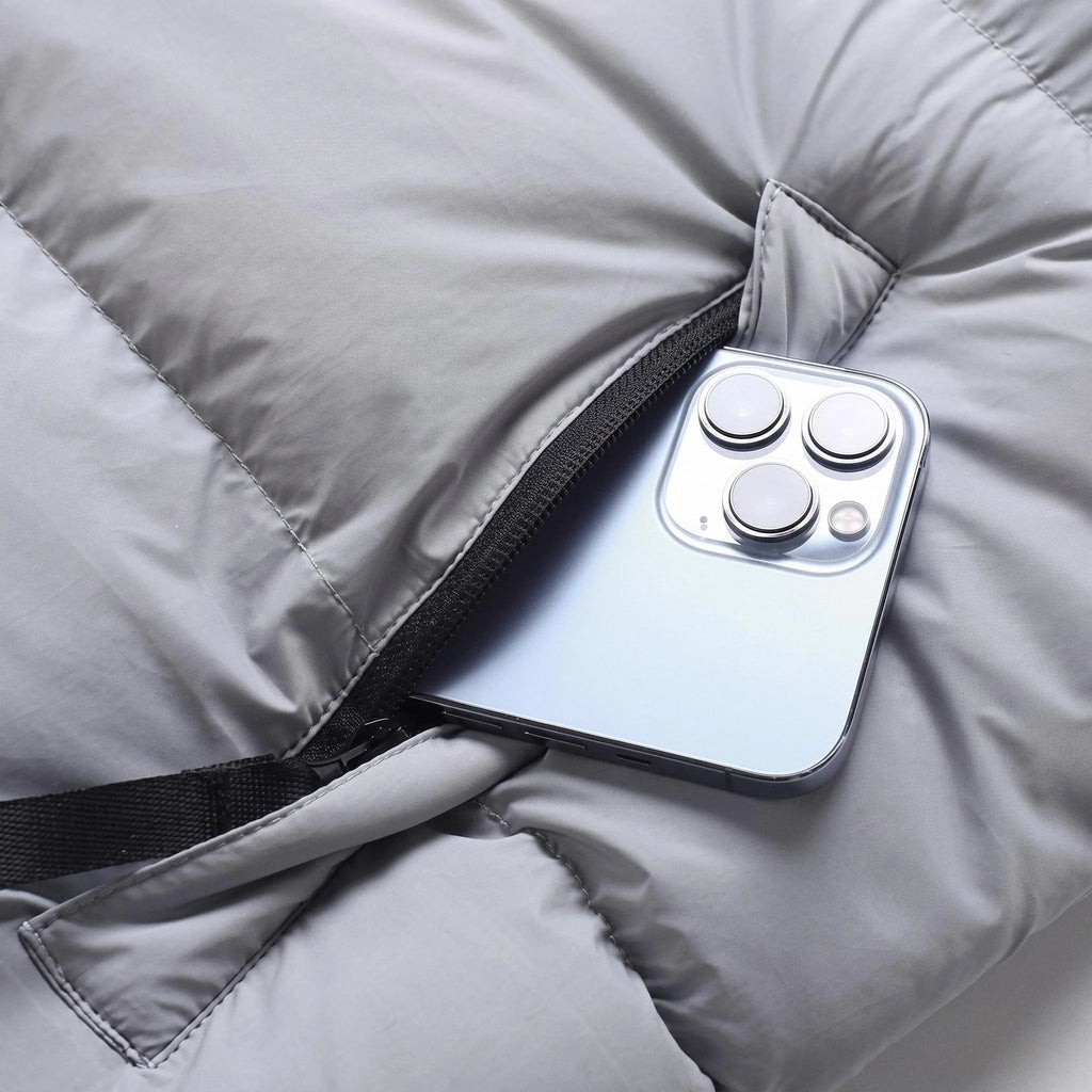 Poche zippée de la doudoune gris clair avec un téléphone glissé dedans