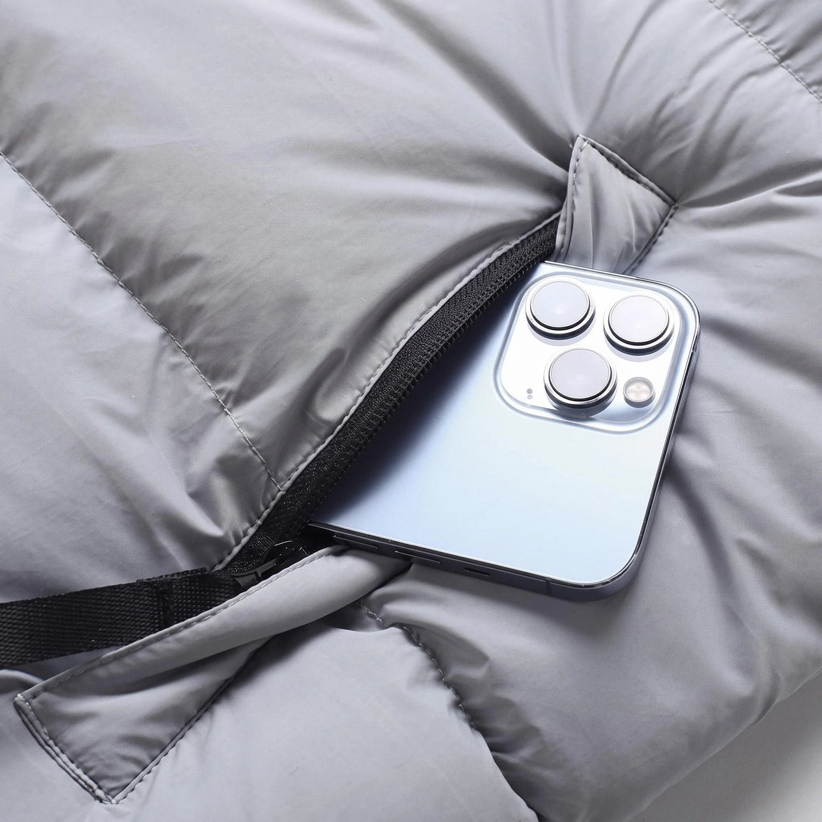 Poche zippée de la doudoune gris clair avec un téléphone glissé dedans