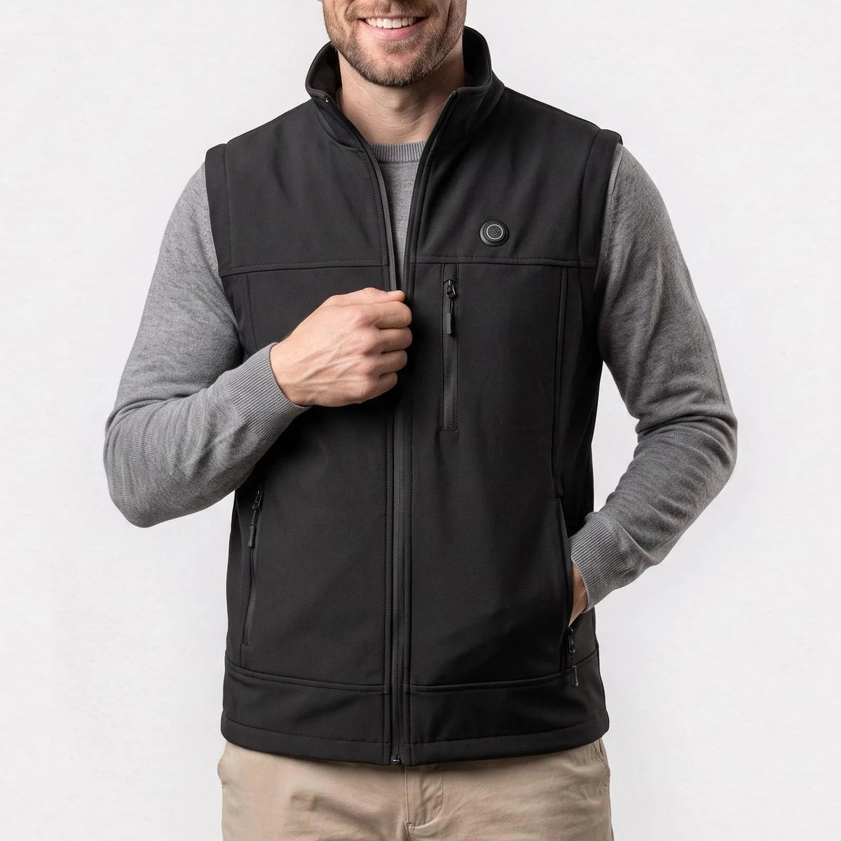 Gilet softshell chauffant noir porté par un homme souriant, une main sur la fermeture
