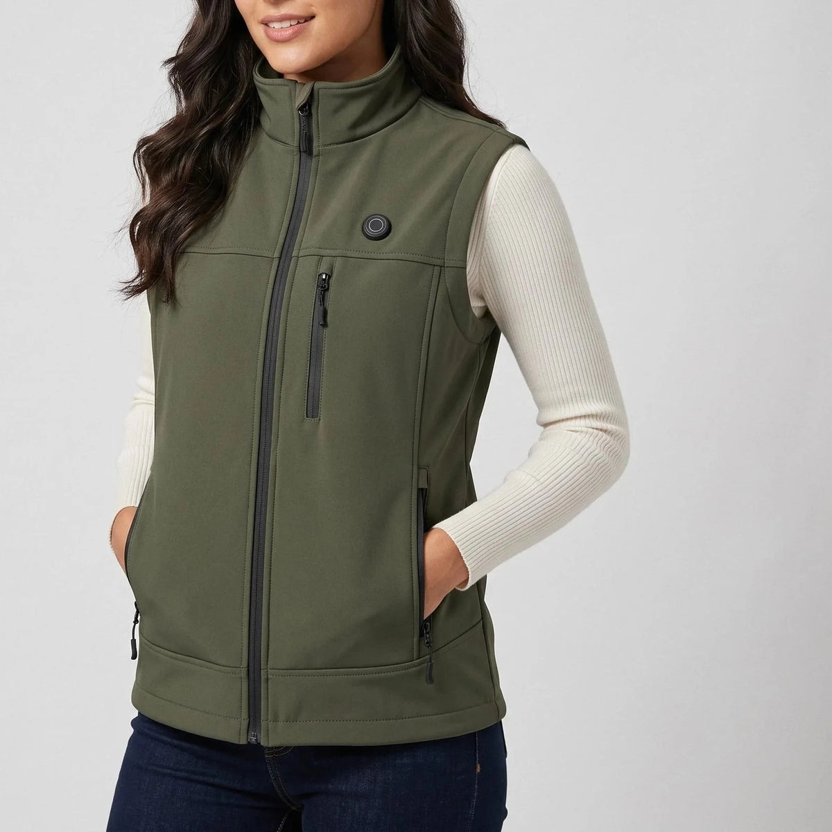Gilet softshell chauffant vert olive porté par une femme, les mains dans les poches