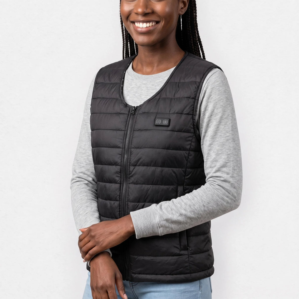 Gilet chauffant léger noir à col en V porté par une femme souriante, les mains croisées