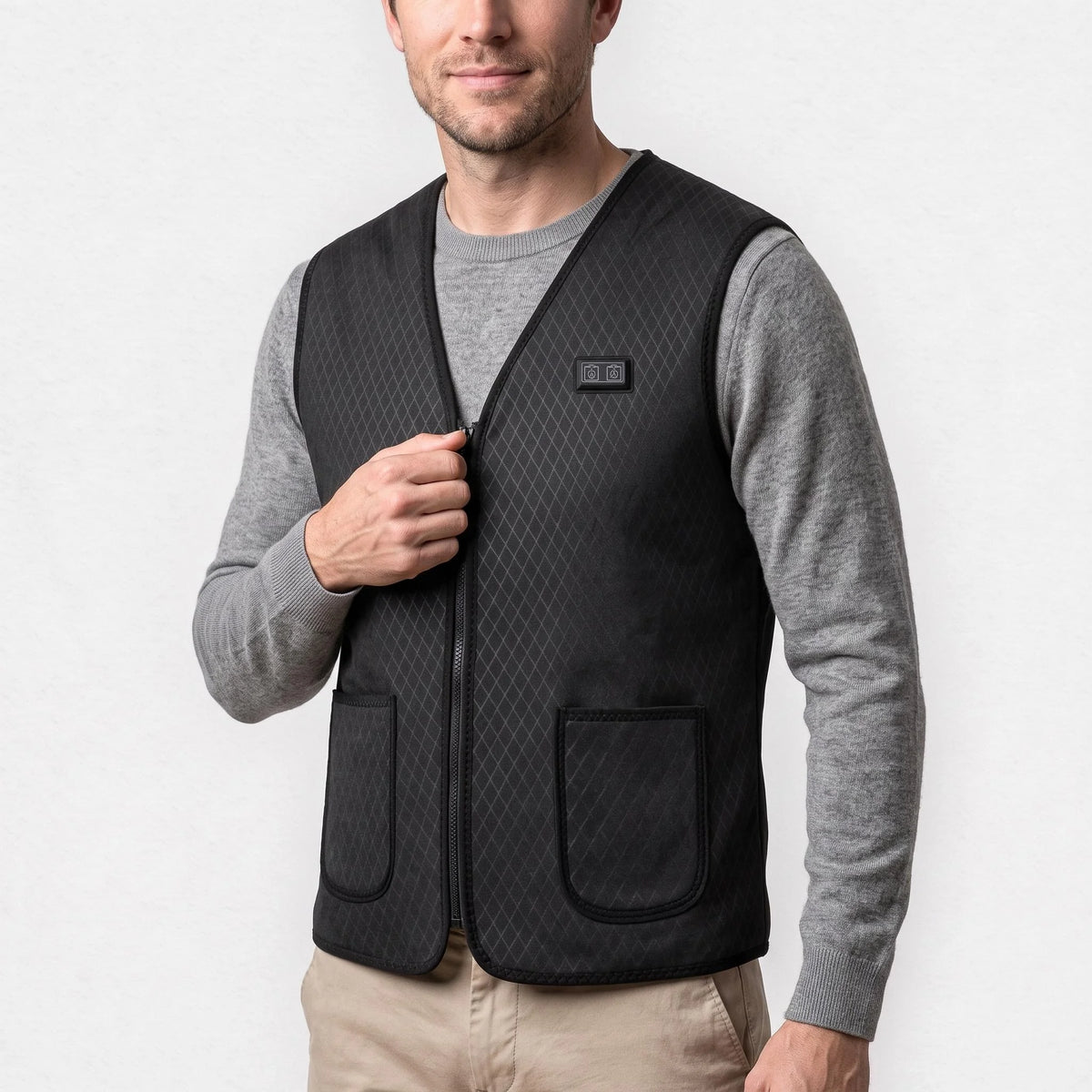 Gilet chauffant fin noir à col en V porté par un homme souriant, une main sur la fermeture