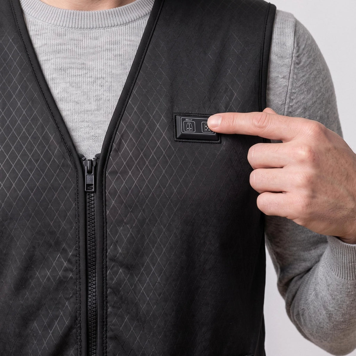 Un doigt appuie sur le bouton de chauffe du gilet fin noir