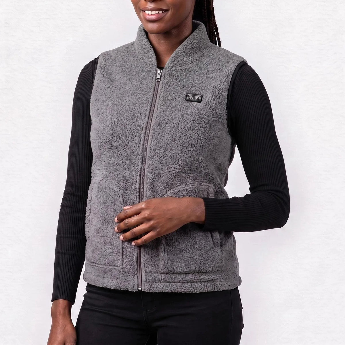 Gilet chauffant en polaire sherpa gris chiné porté par une femme souriante, haut noir