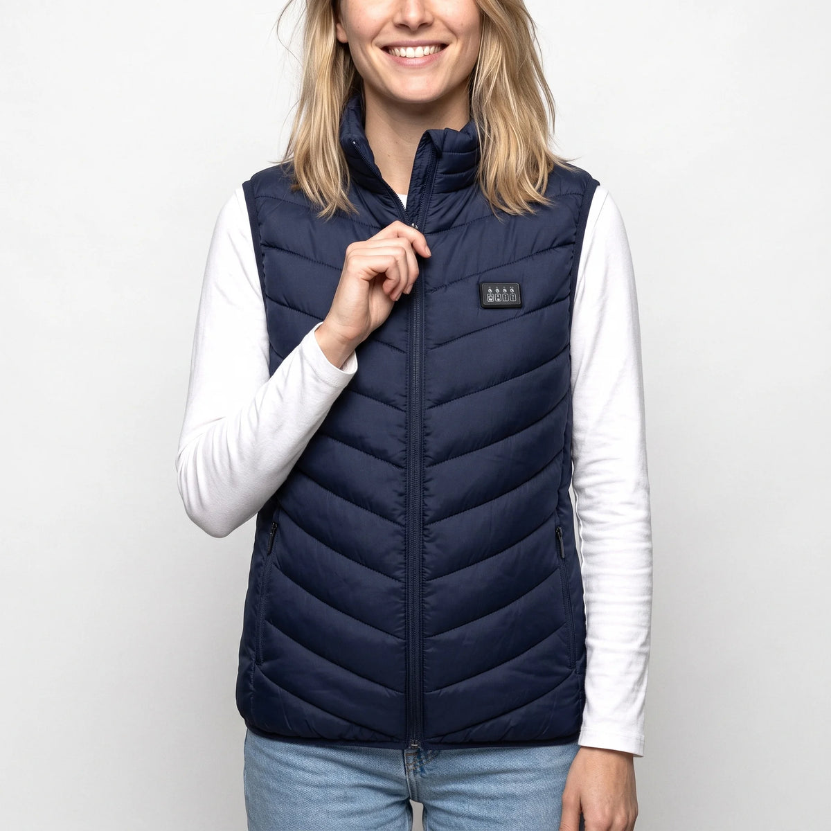 Gilet chauffant bleu marine porté par une femme souriante qui remonte sa fermeture