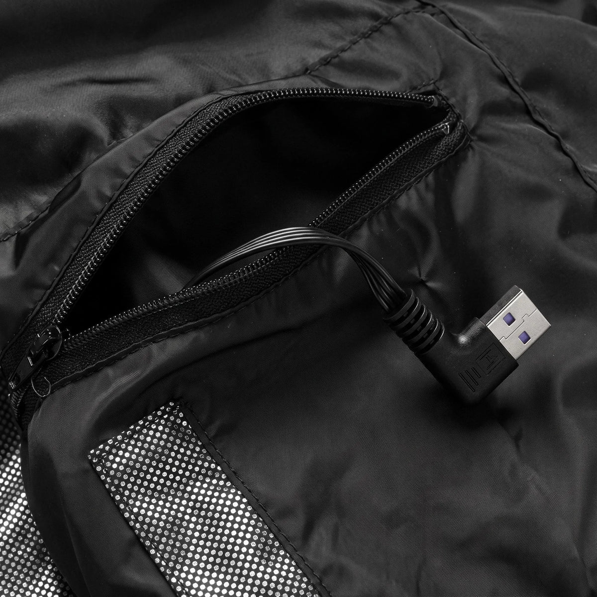 Poche intérieure zippée du gilet avec sa prise USB coudée pour la batterie externe, batterie non incluse