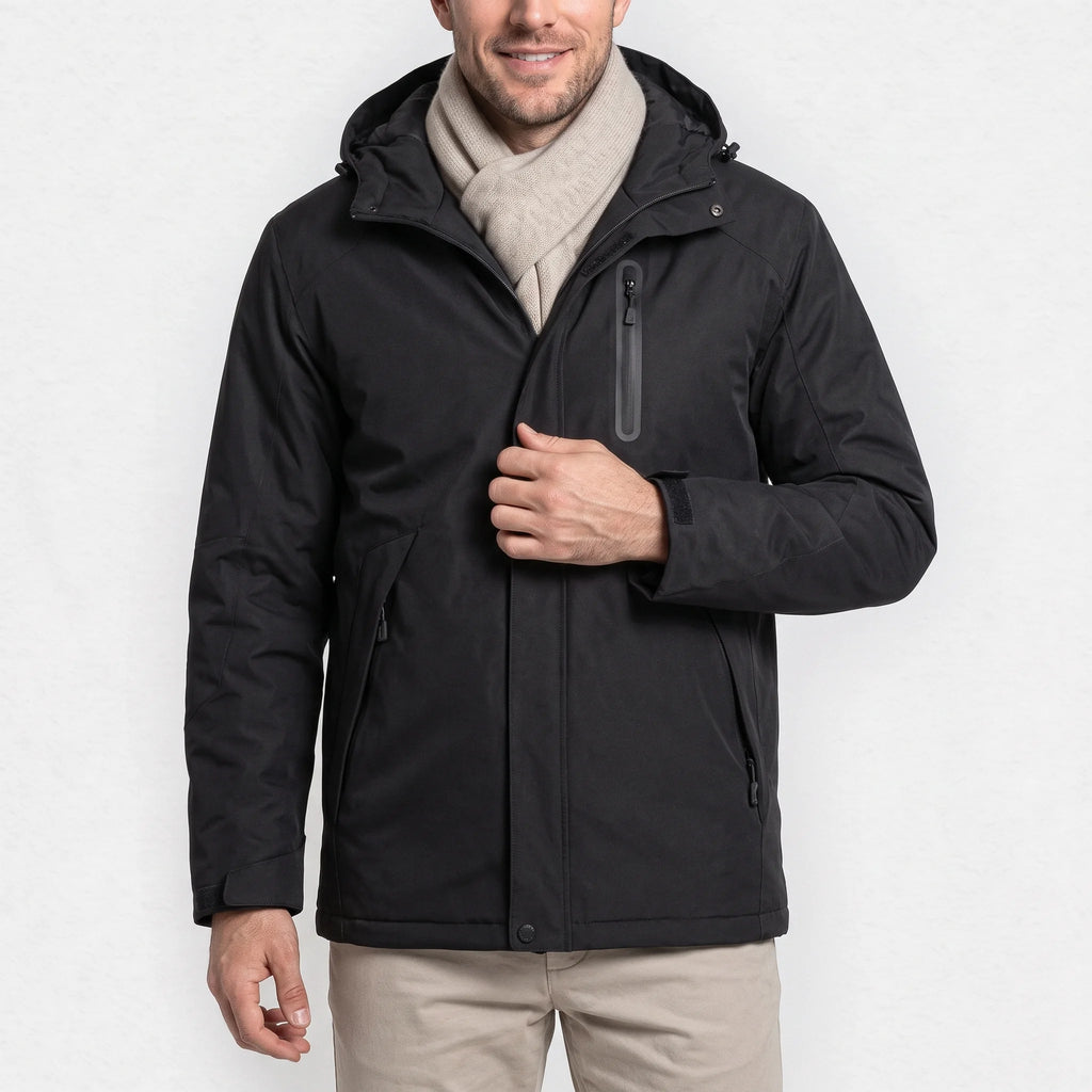 Veste chauffante homme noire à capuche portée par un homme souriant qui tient sa fermeture