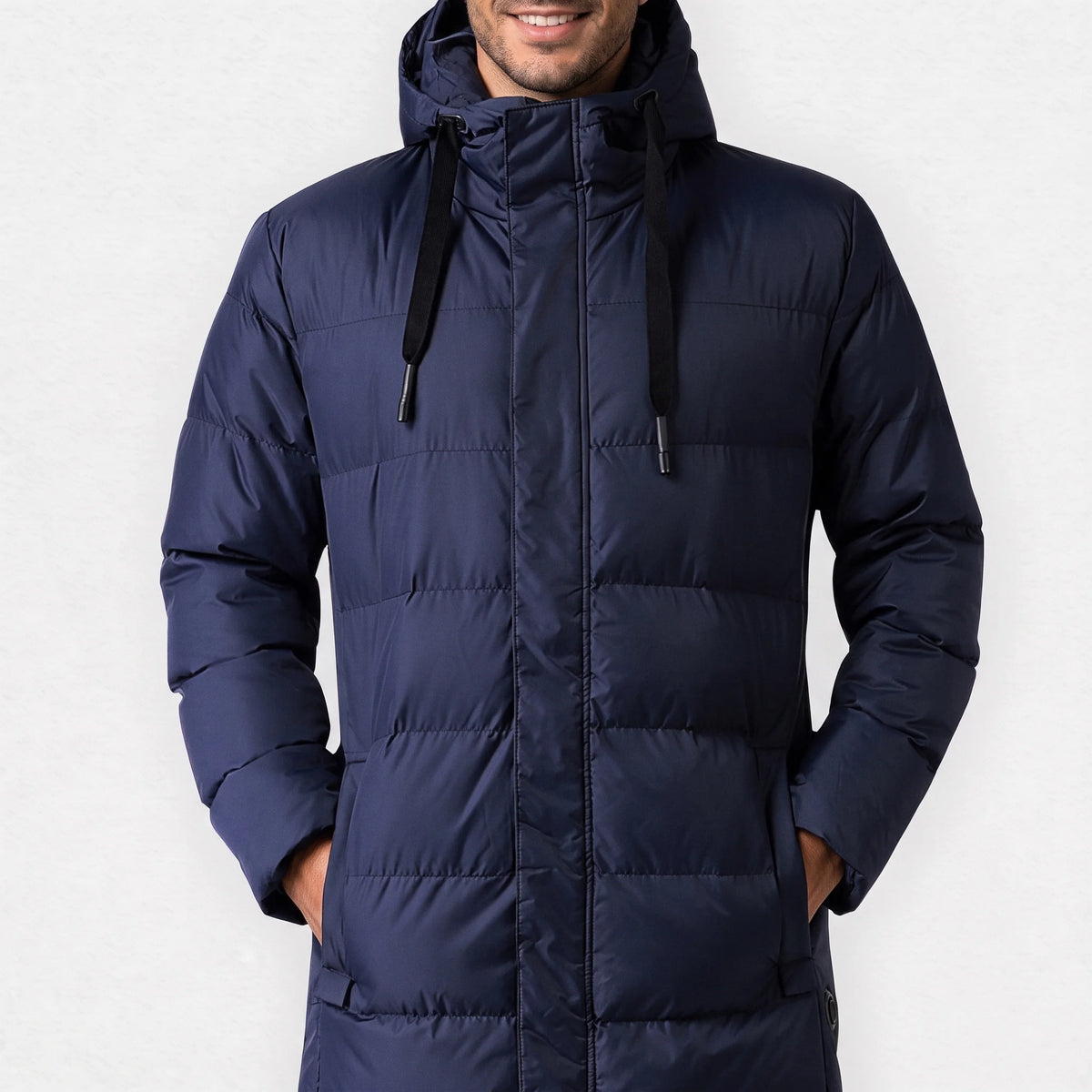 Parka chauffante longue bleu marine à capuche portée par un homme souriant, les mains dans les poches