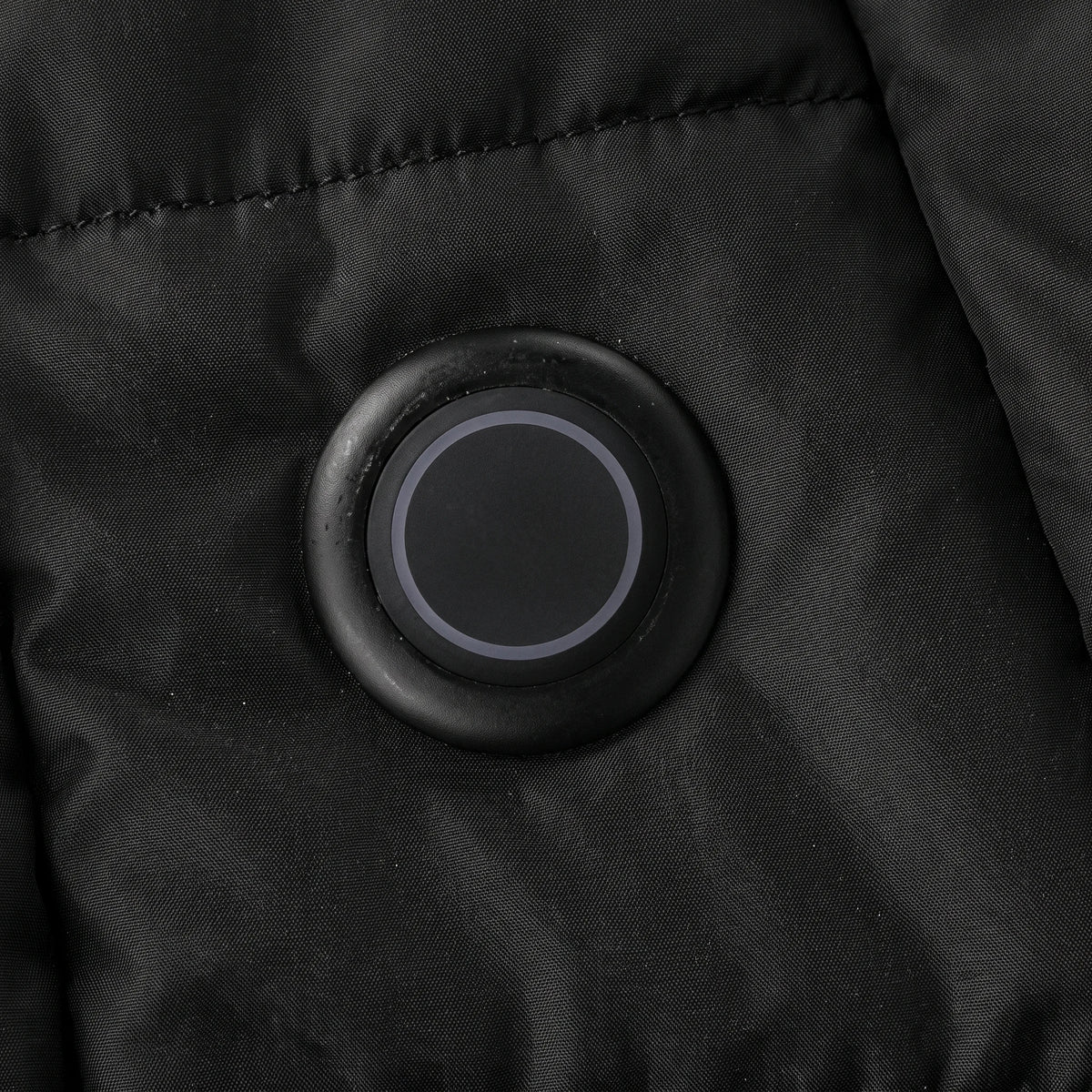 Bouton de chauffe rond et lumineux sur le bas du devant de la parka