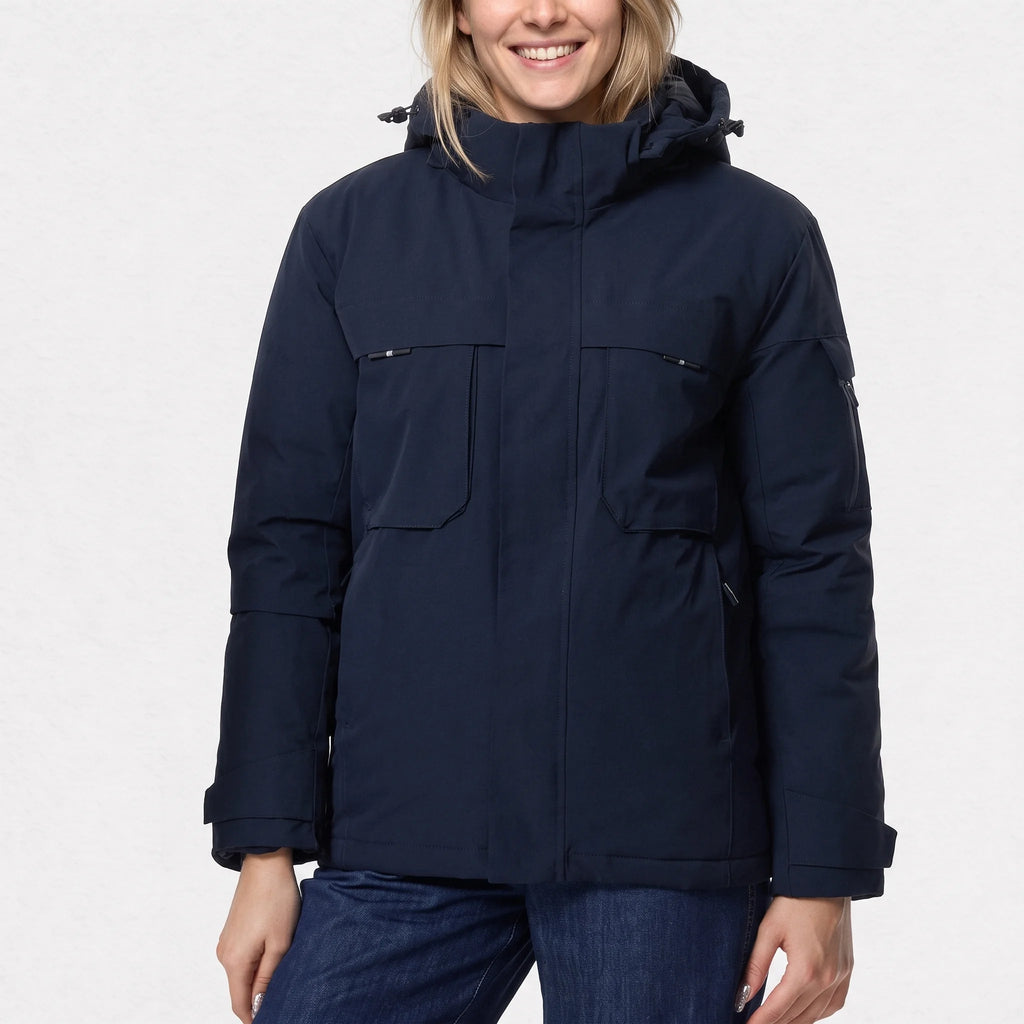 Parka chauffante courte bleu marine portée par une femme souriante, poches de poitrine à rabat