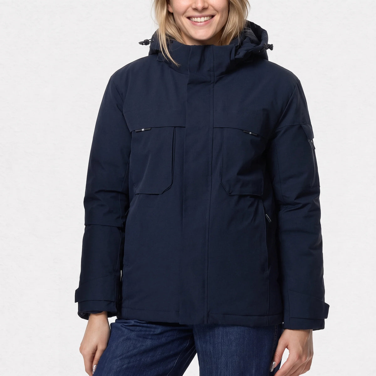 Parka chauffante courte bleu marine portée par une femme souriante, poches de poitrine à rabat