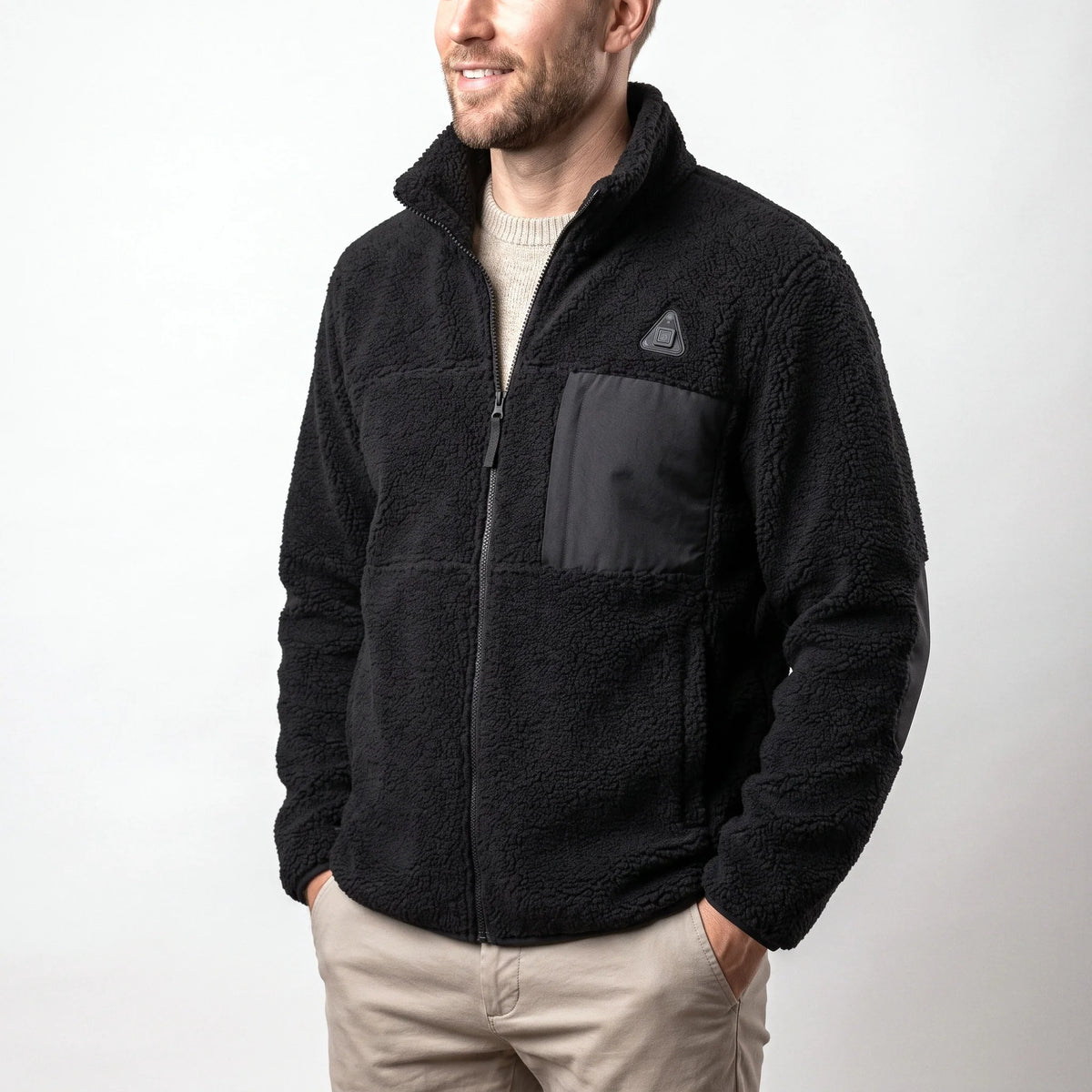 Veste polaire sherpa chauffante noire portée par un homme souriant, les mains dans les poches