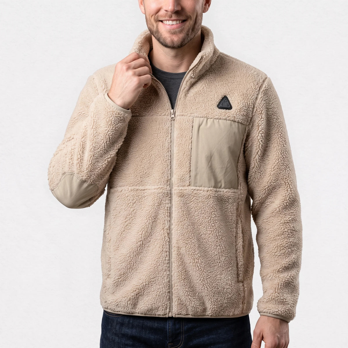Veste polaire sherpa chauffante sable portée par un homme souriant qui tient son col