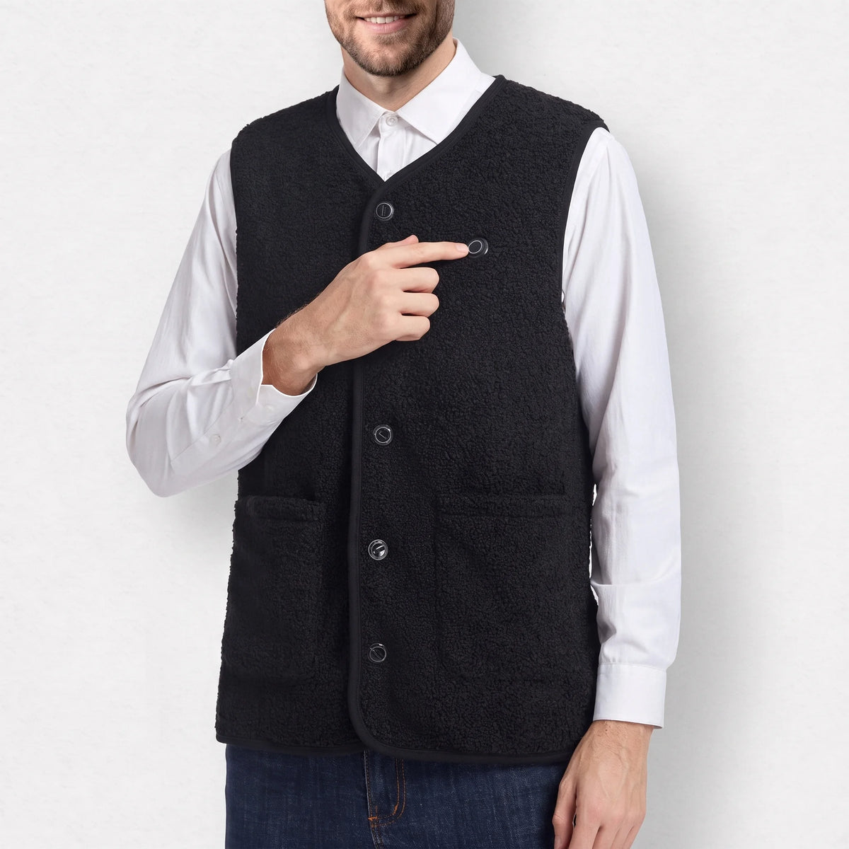 Gilet chauffant sherpa noir porté par un homme qui montre le bouton de chauffe