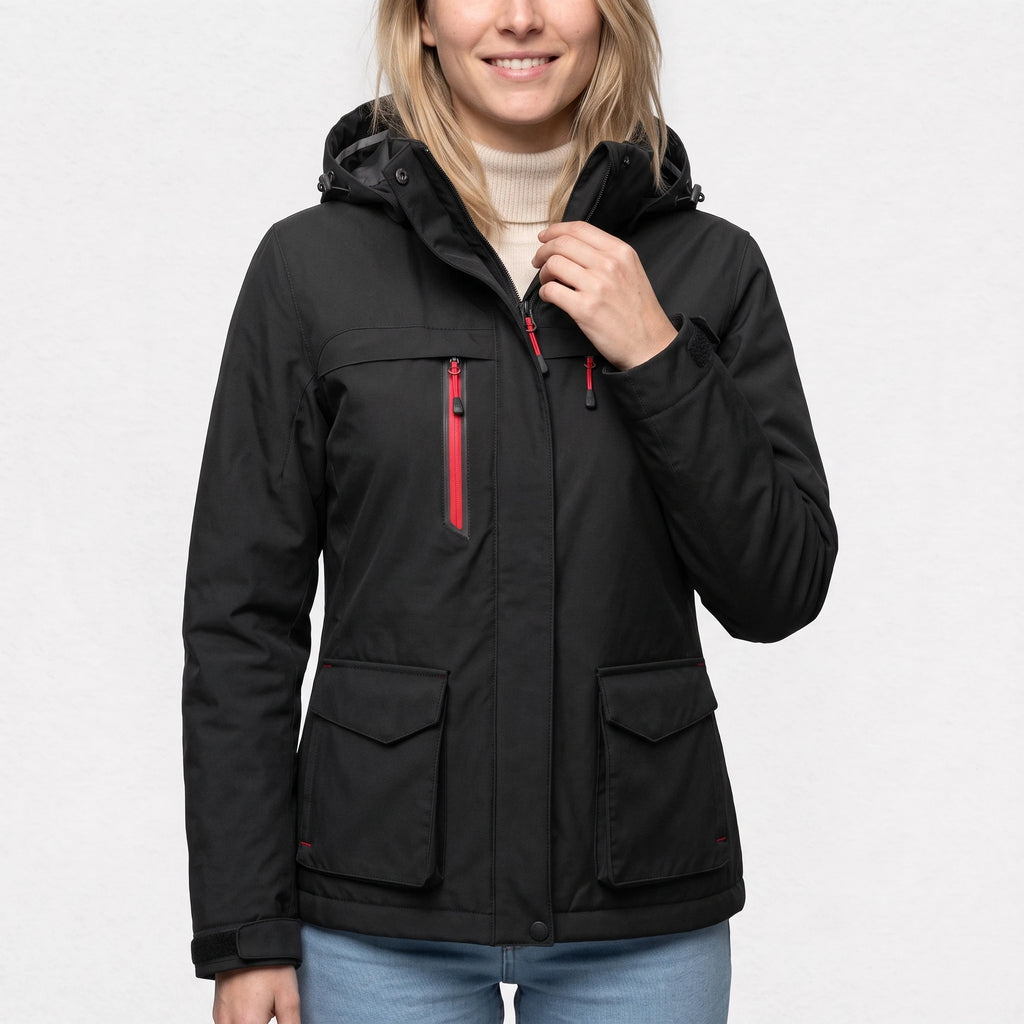 Veste de ski chauffante noire portée par une femme souriante, une main au col
