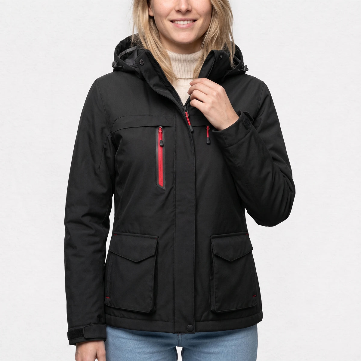 Veste de ski chauffante noire portée par une femme souriante, une main au col