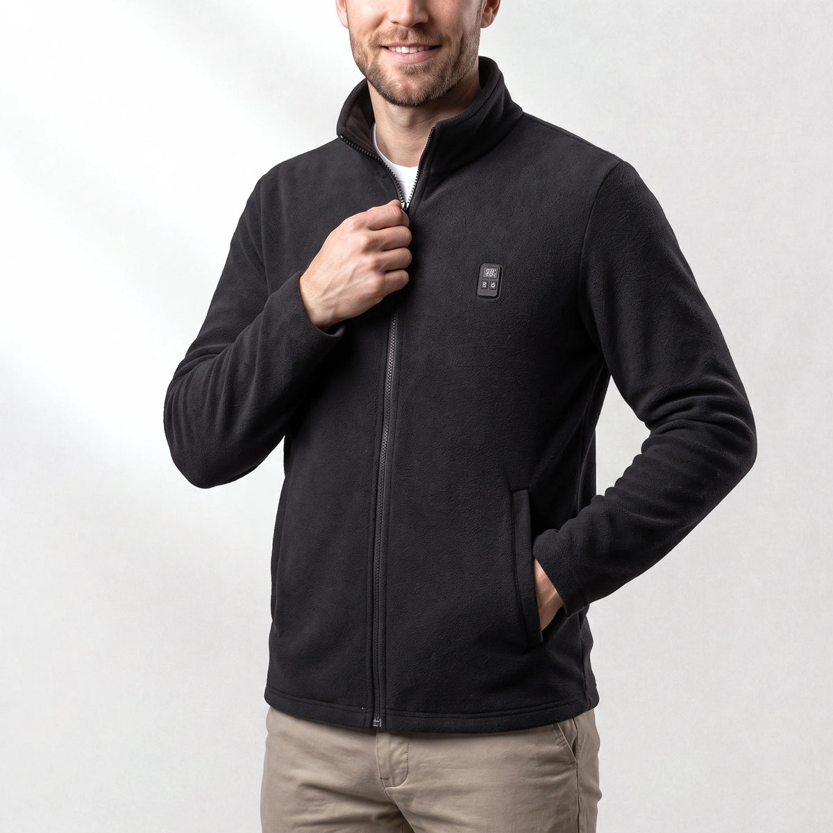 Veste polaire chauffante noire portée par un homme souriant, une main dans la poche